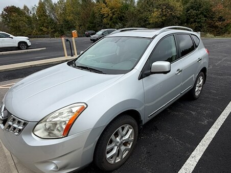 Courtesy car two at Russell County Airport: a silver Nissan Rogue seen from the front left in the airport car park, with other parked vehicles and the treeline beyond
