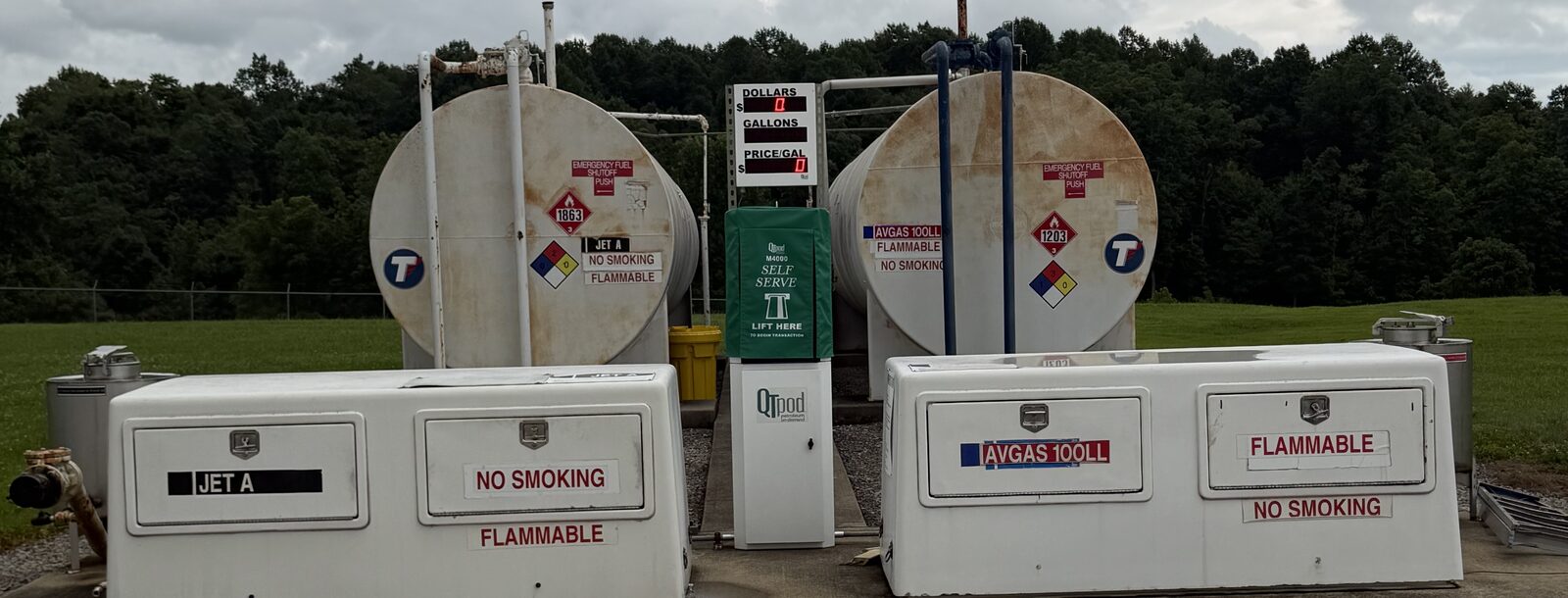 The self-serve fuel island at Russell County Airport: the Jet A and AVGAS 100LL cabinets flanking a card-reader kiosk, with the two bulk tanks behind them